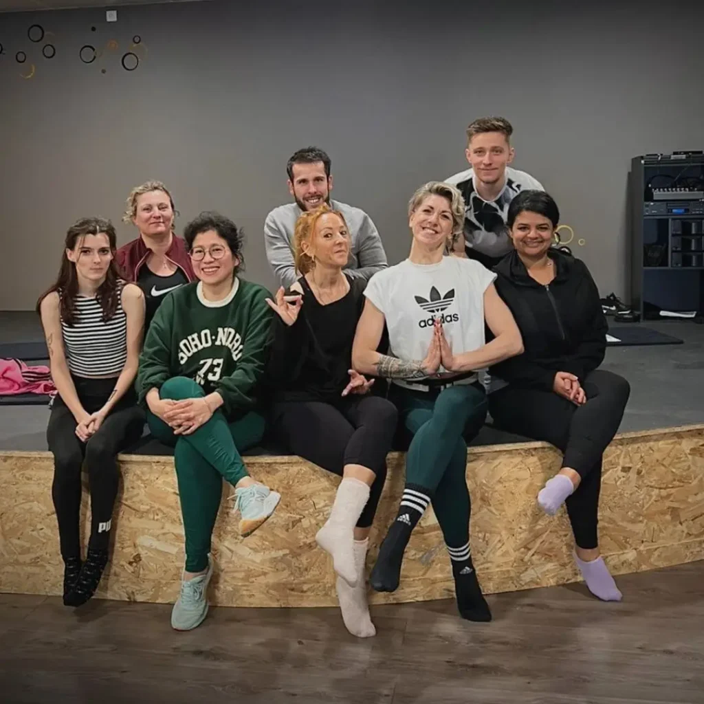 Groupe de huit personnes souriantes dans une salle de sport.