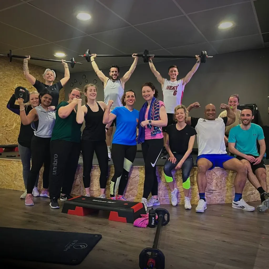 Groupe joyeux posant après entraînement en salle.