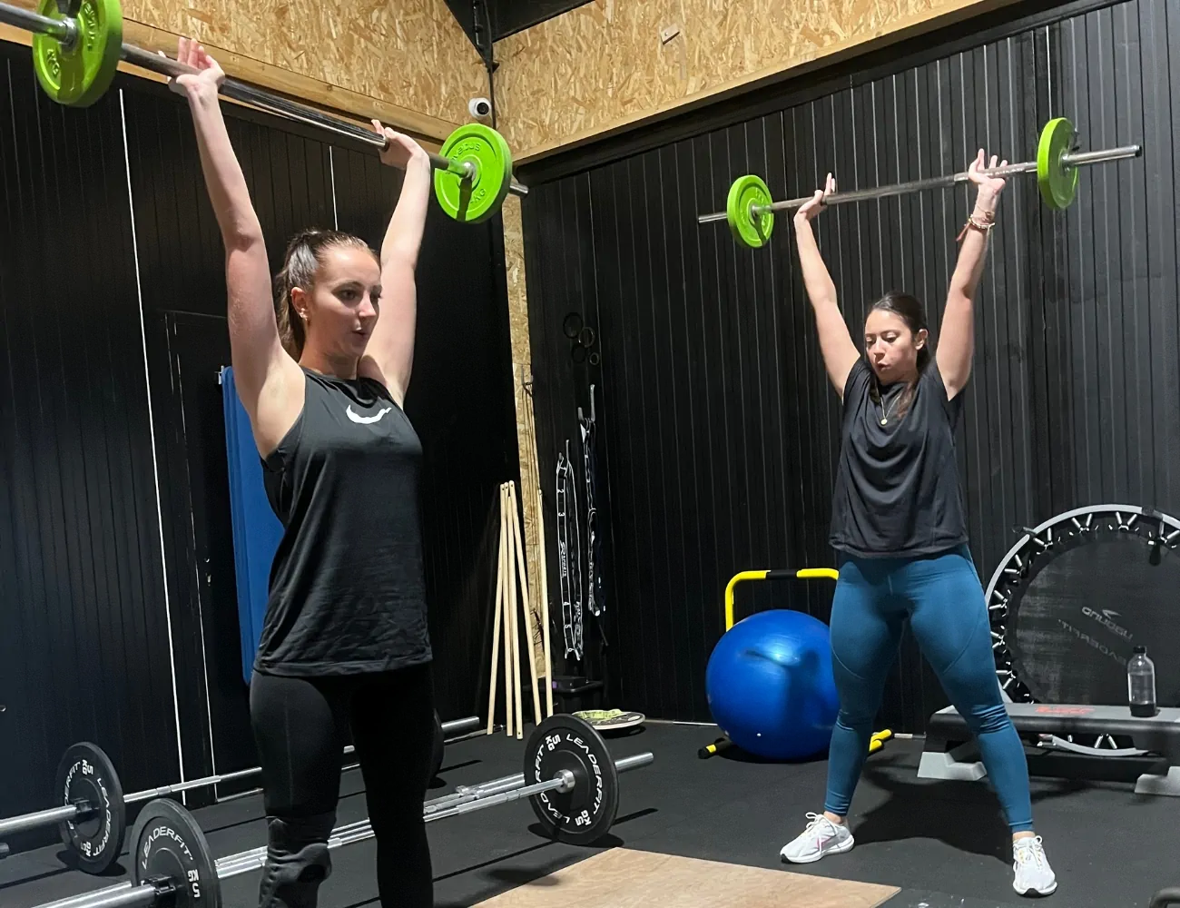 Deux femmes soulèvent des haltères dans une salle de sport.