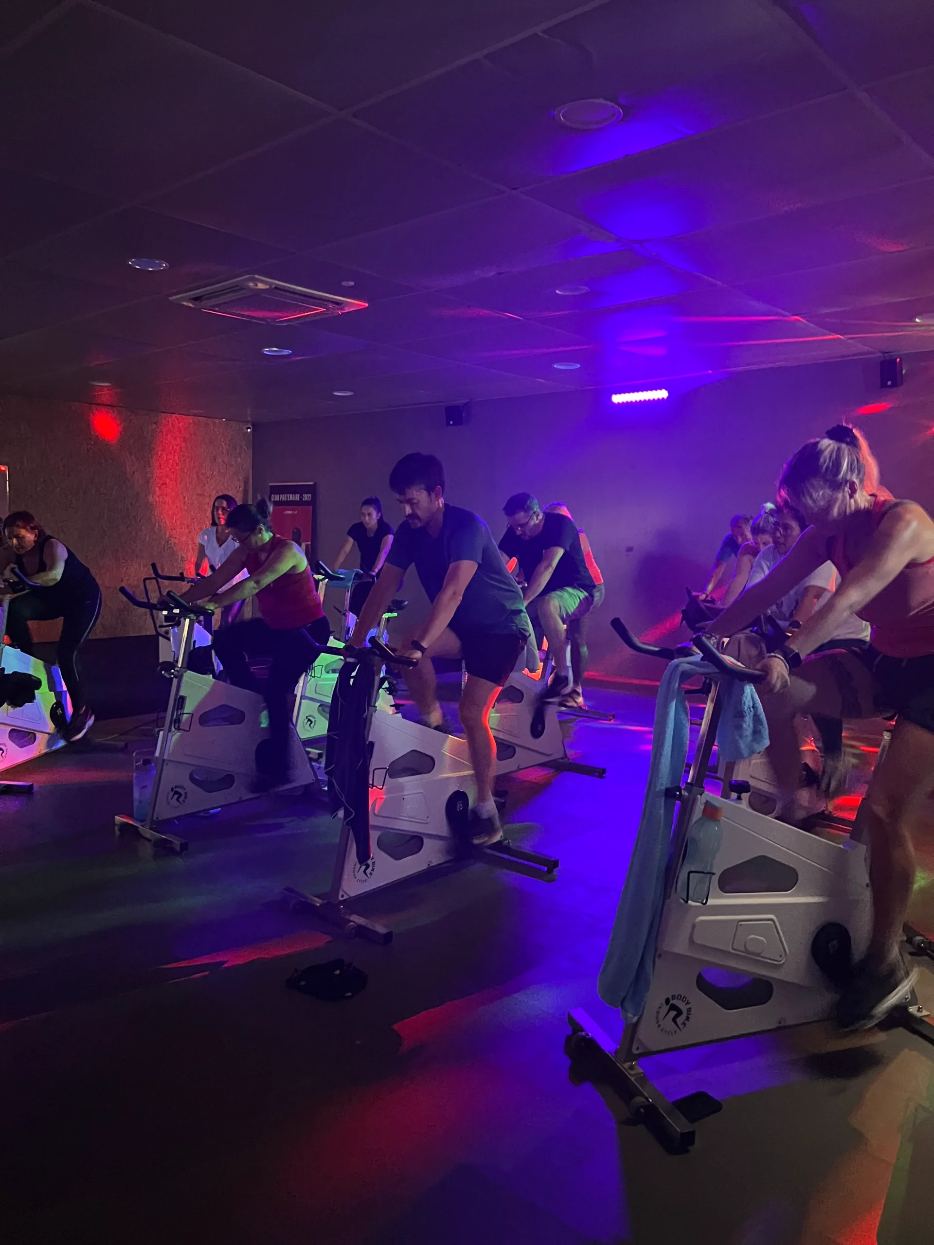 Groupe faisant du vélo en salle éclairée colorée