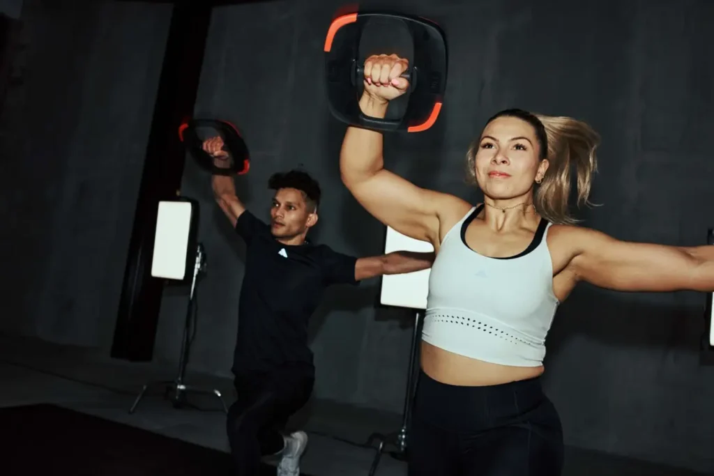 Deux personnes s'entraînent avec haltères dans gym sombre